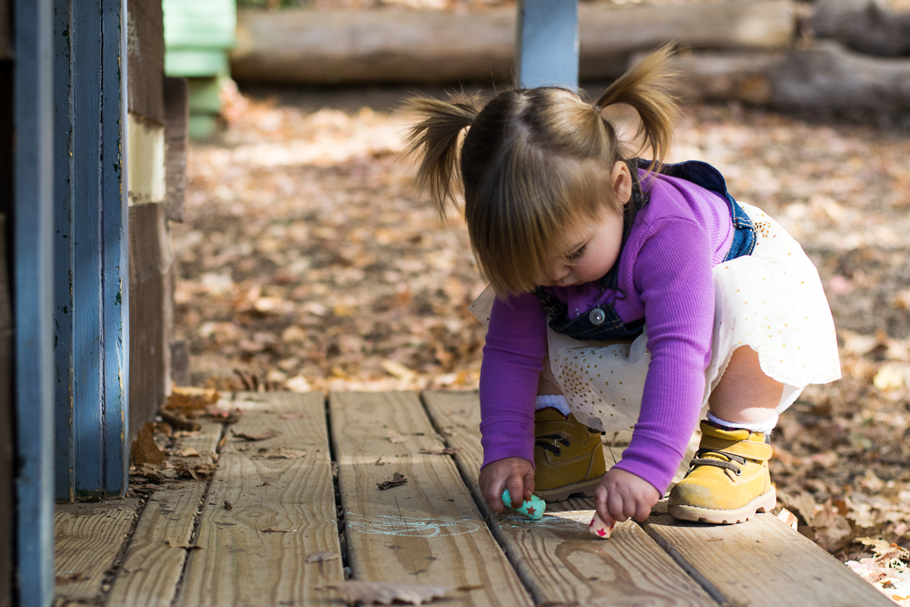 A toddler writing with chalk at Ijams Nature Center.