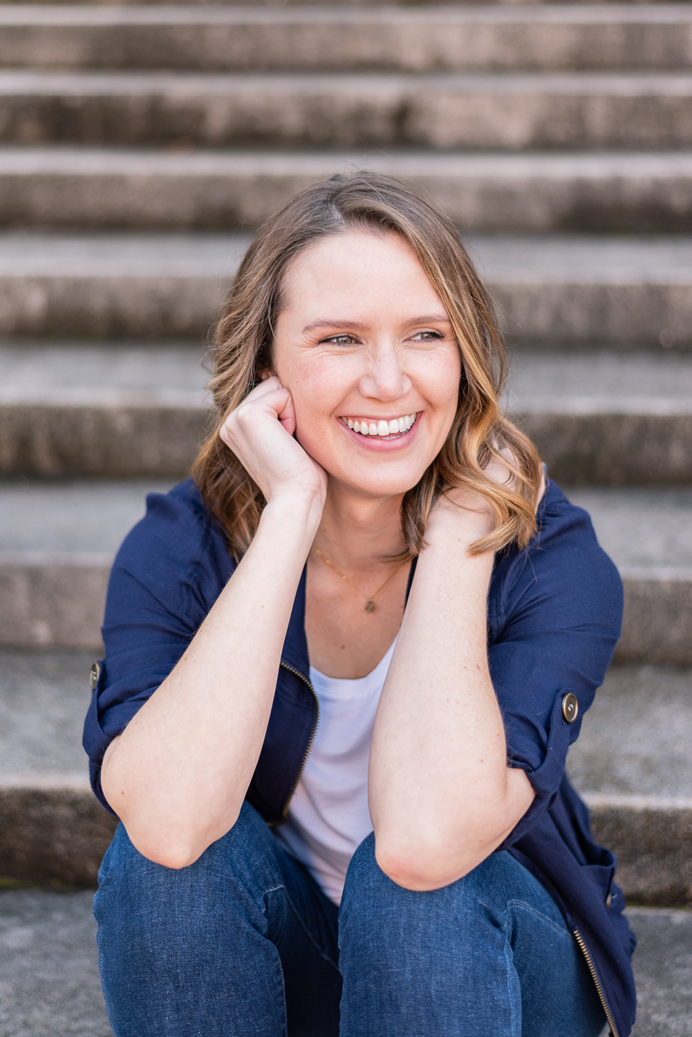 Branding headshot of a woman sitting on steps and laughing in downtown Knoxville, TN.