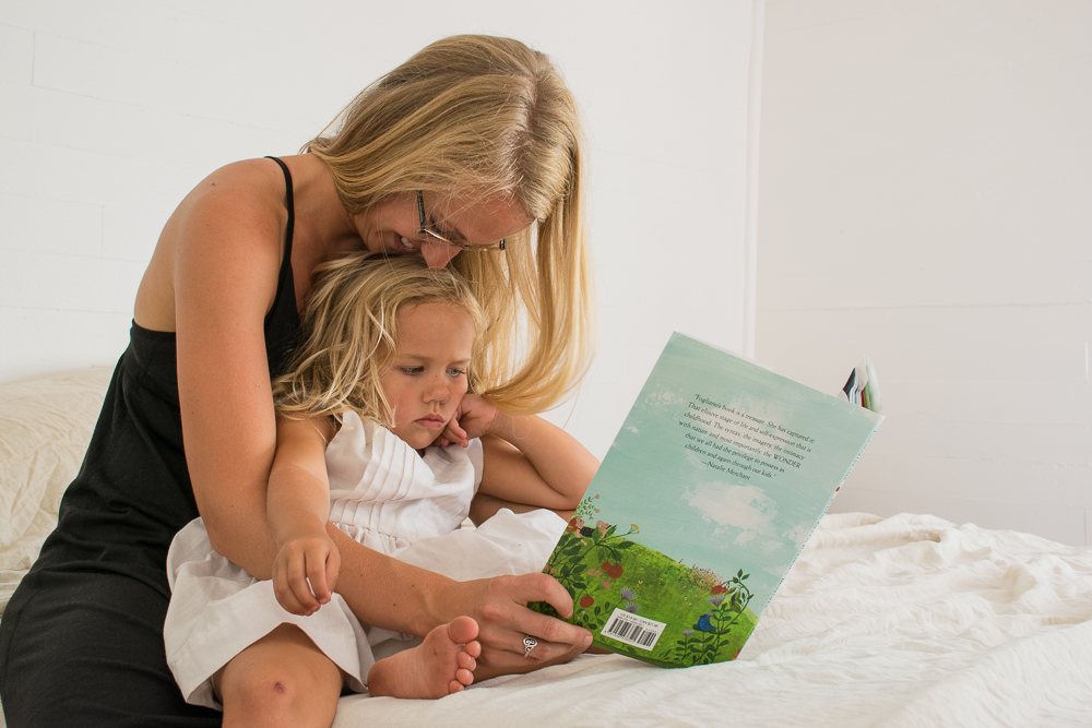 Mother and daughter read a book for story time in the bedroom.