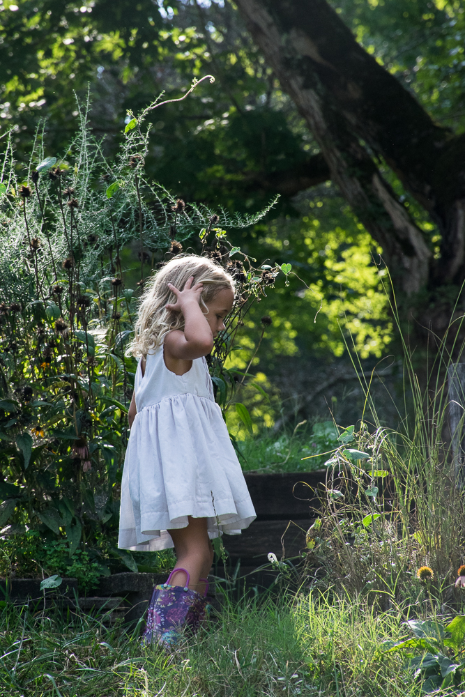 A little girl plays in the garden in the summer sun.
