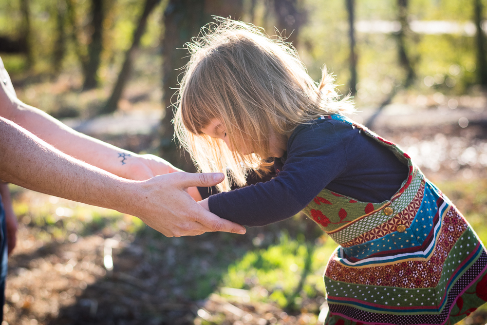 A young girl reaching for her mother's arms in the glowing sunlight.