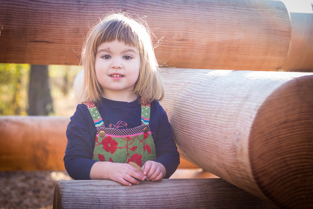 A young girl playing on logs at the Baker Creek Preserve playground.