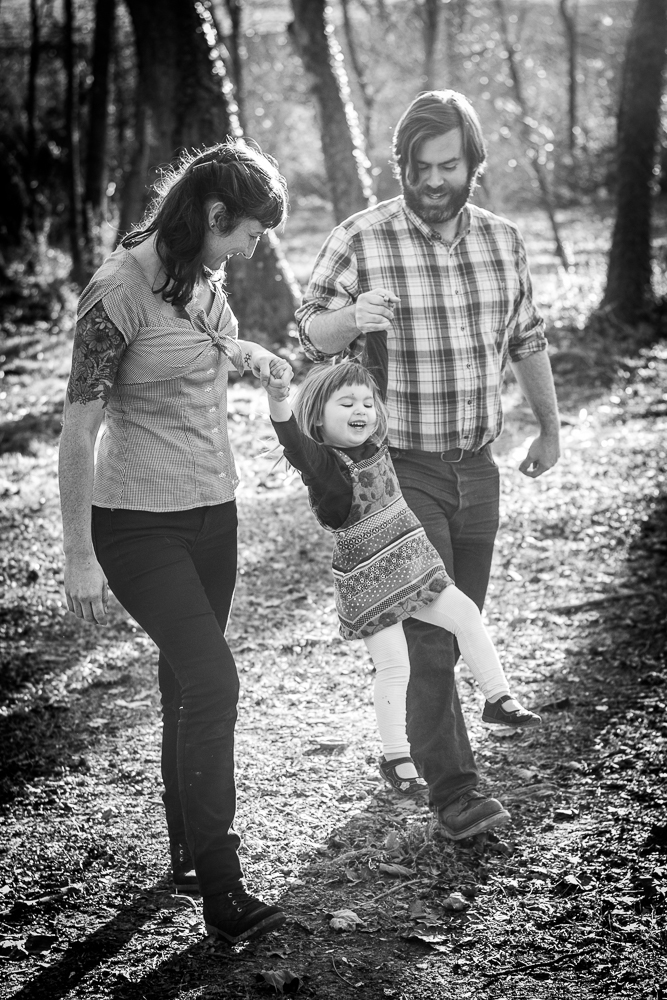 Family of three walking and playing in the forest.