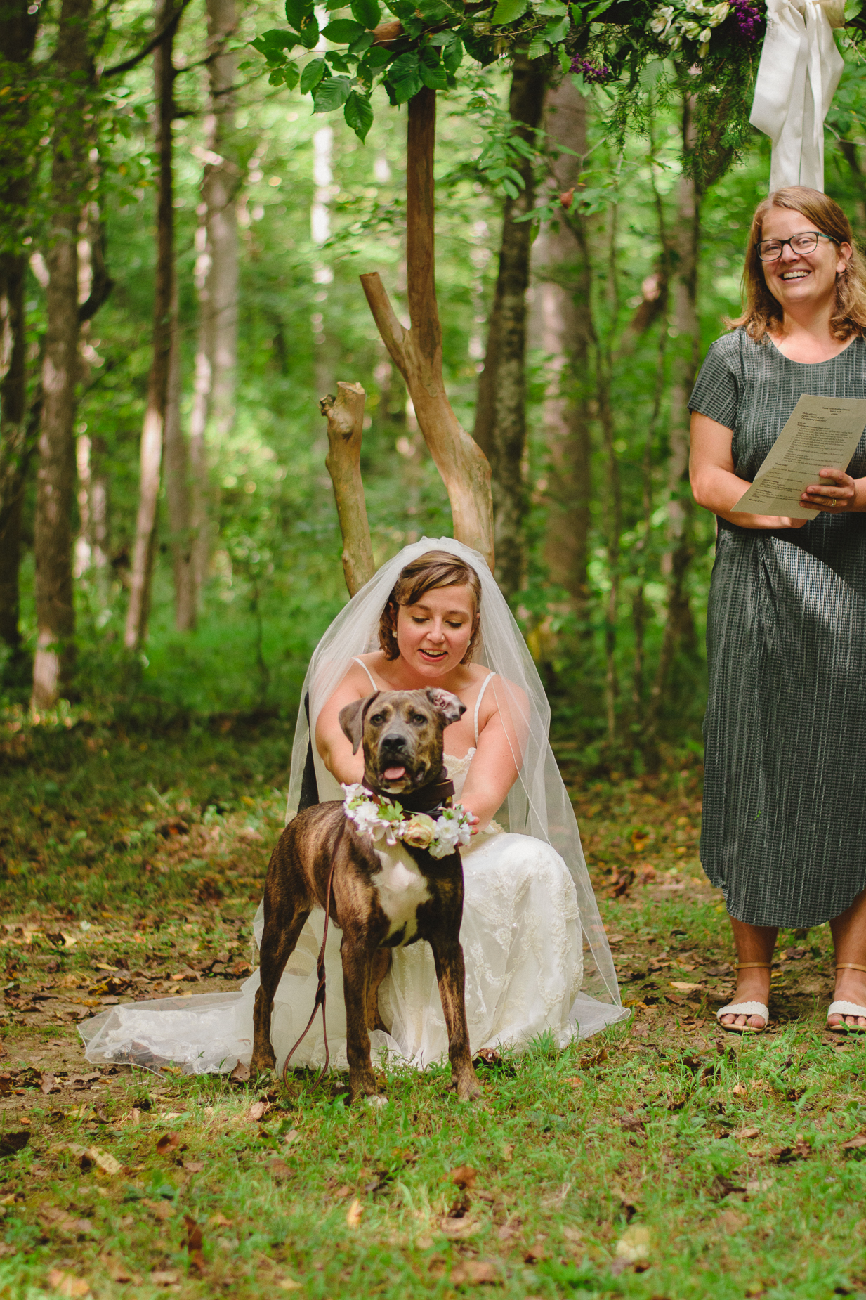 Bride holds the ring bearer dog at her wedding.