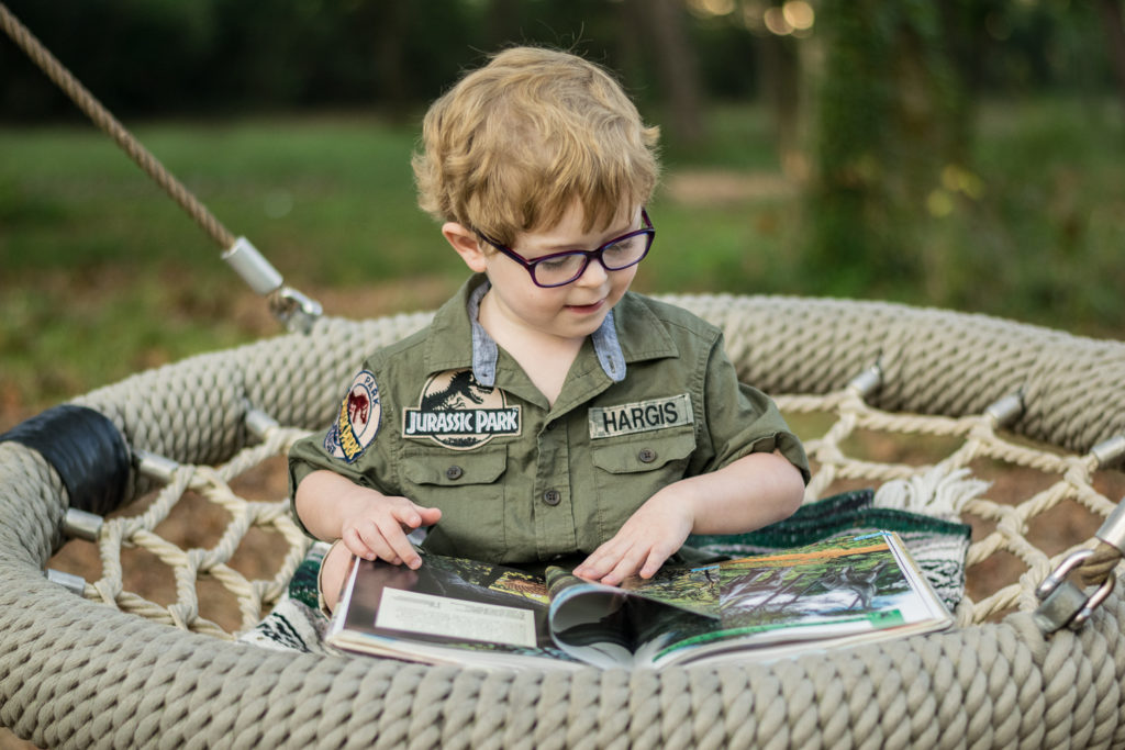 Young boy reading a dinosaur book at Baker Creek Preserve.
