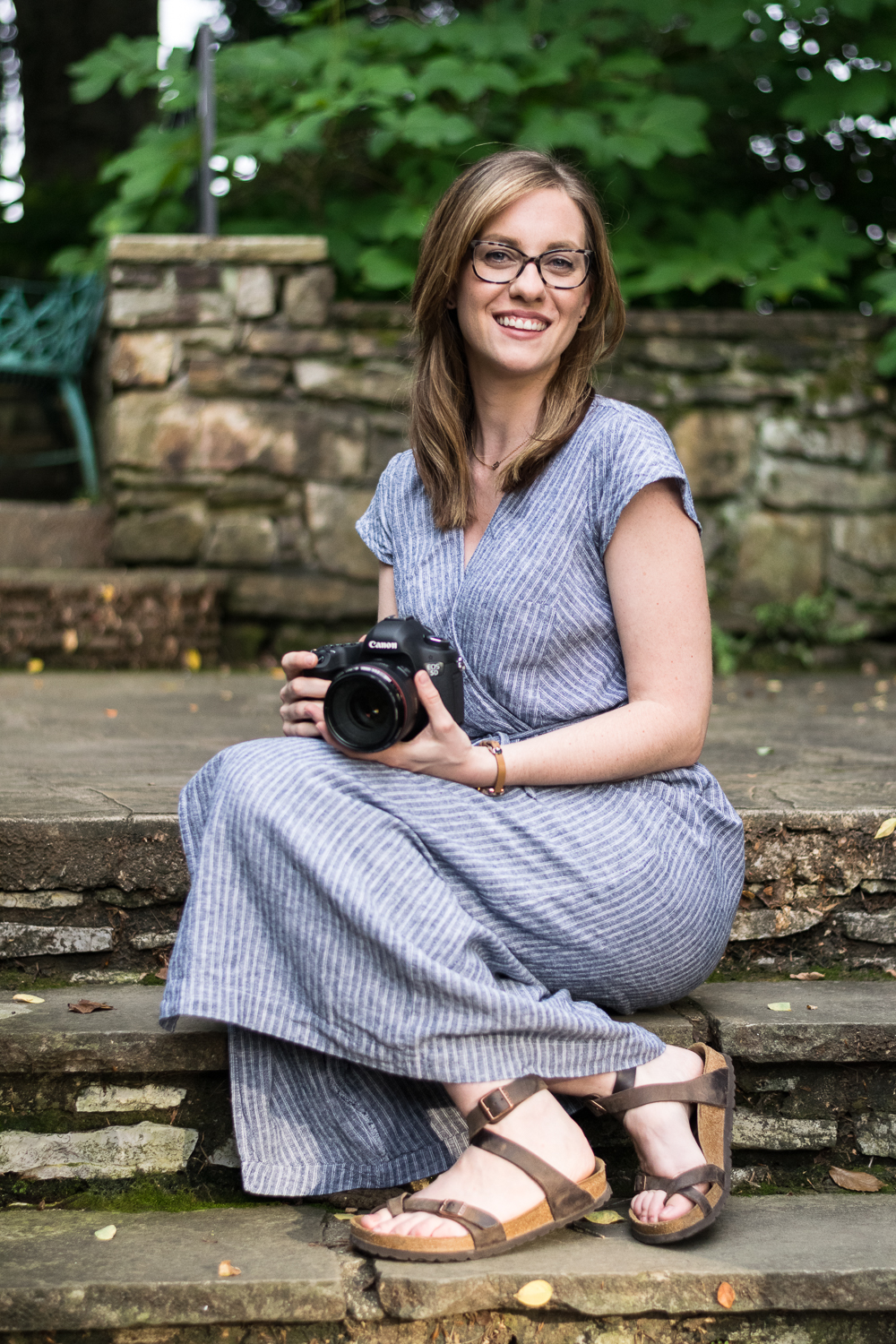 Knoxville photographer Krista Weatherholt sits on stone steps while holding her camera.