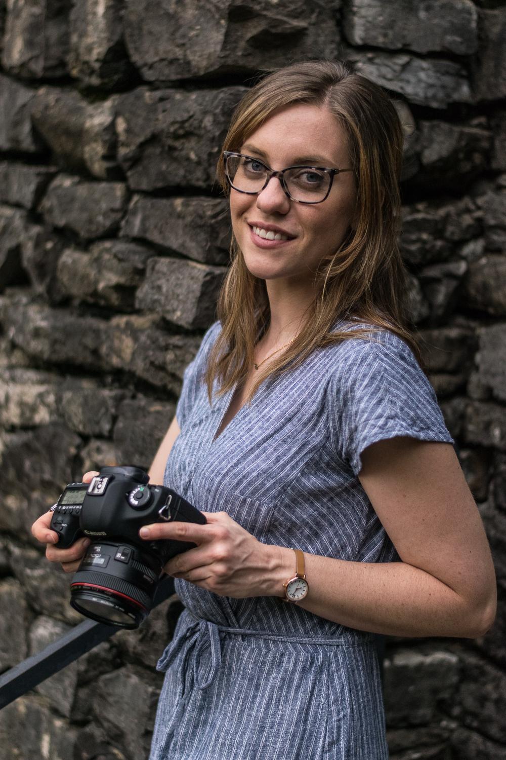 Knoxville photographer Krista Weatherholt holding her camera by a stone wall.