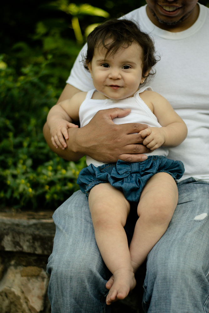 Baby girl smiling, sitting in her father's lap.