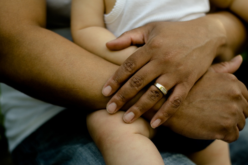Close-up of a father's hands holding his baby girl.