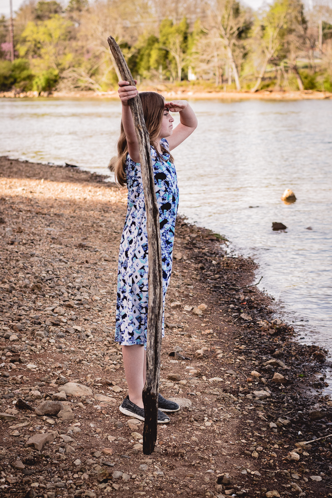 A young girl pretending to be an explorer at the shoreline.
