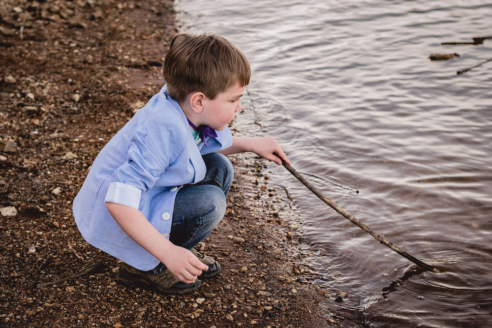 Young boy playing with a stick along the Tennessee River.