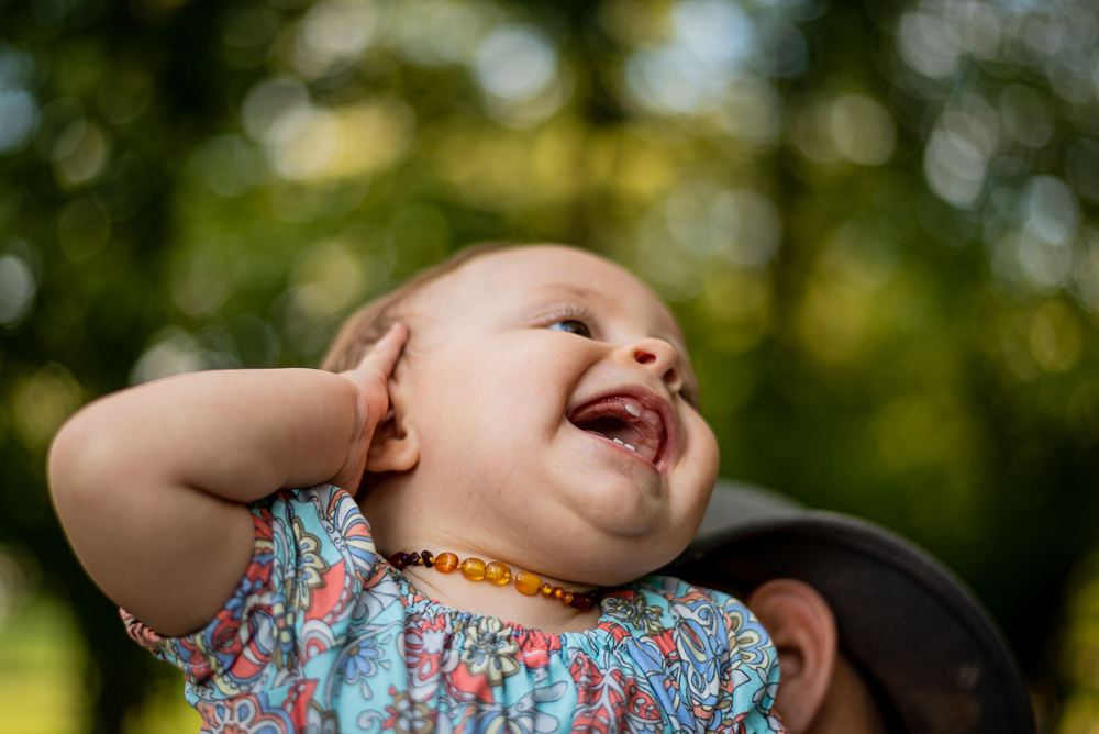 A baby girl laughs and shows her three tiny teeth.