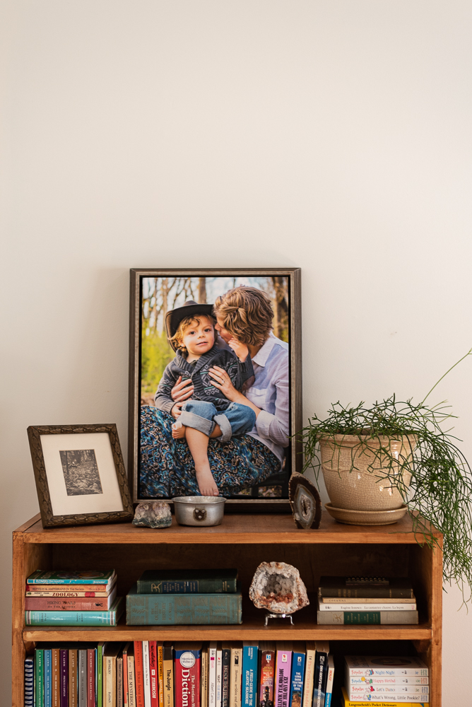 A printed photograph of a little boy and his mother sits atop a shelf.