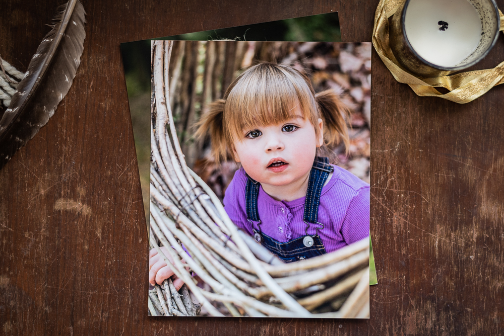 Printed photos of a toddler sit on a wooden chest.