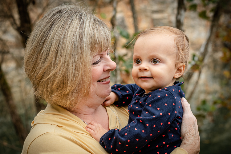 A grandmother holds her baby granddaughter and smiles.