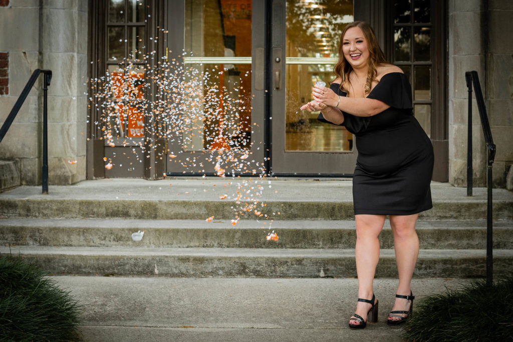 A UT student at Morgan Hall pops confetti to celebrate graduation.
