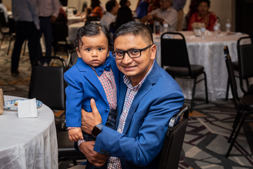 A man and his son in matching suits at a Bratabandha ceremony.