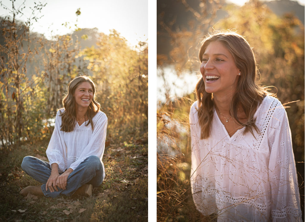 A female high school senior in a white blouse sits for senior portraits by the river at Sequoyah Park.