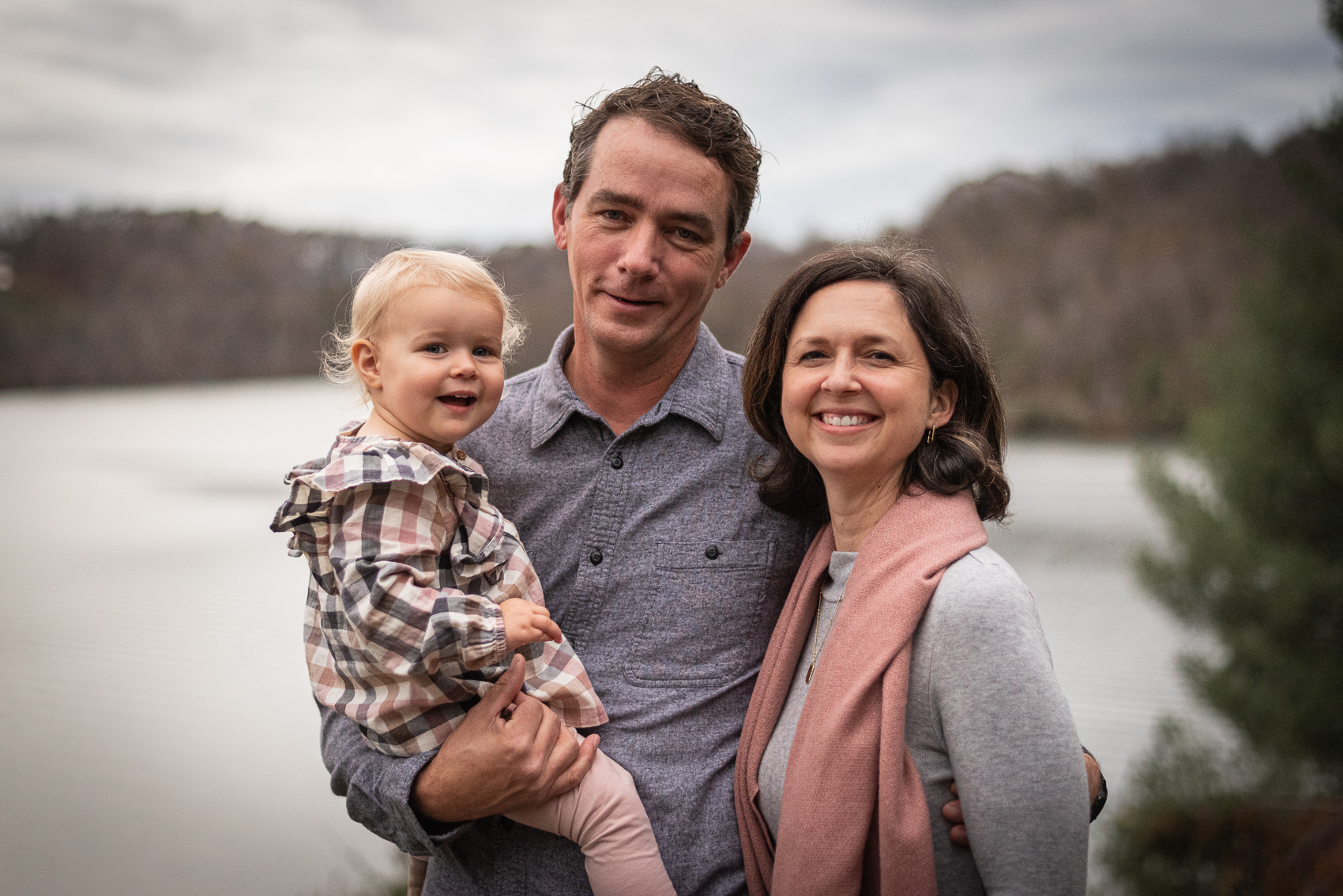 A mother, father, and toddler stand in front of the Tennessee River.