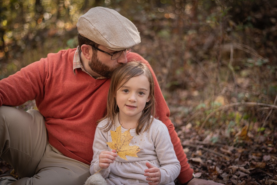 In the forest, a father kisses his young daughter on the head.